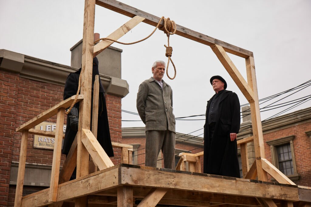 Rob Stewart as Andrew May Sr. and Darren Stewart as the Hanging Official in Slasher: Ripper (Season 5, Episode 2). Photo Credit: Nikki Ross /Shudder